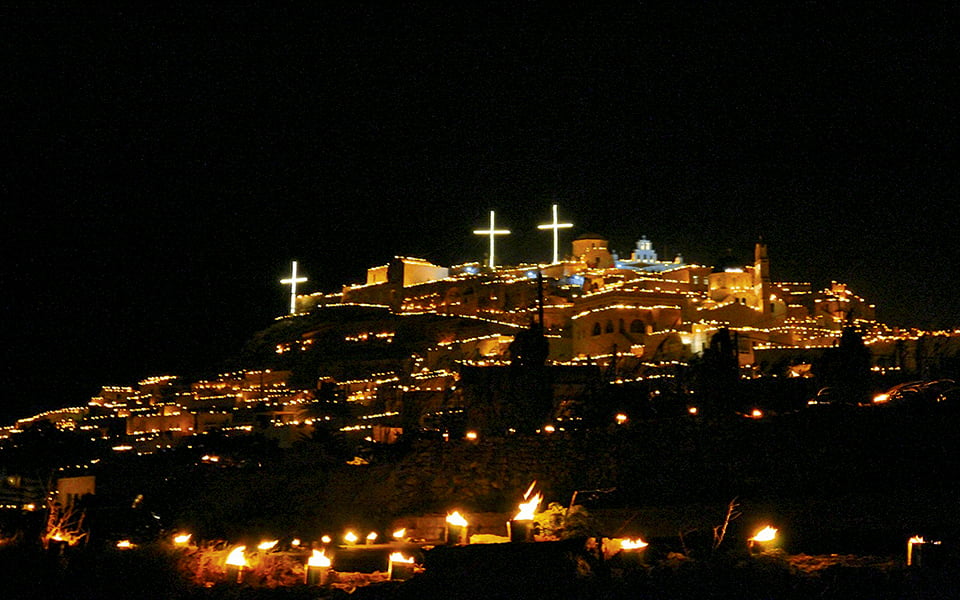Pyrgos Santorini on Good Friday | Easter in Greece The village of Pyrgos in Santorini as seen from afar on Good Friday. The streets, alleys and roof tops are filled with custom candles that are lite up while the Epitaph goes through the village as a Greek local Easter customs. This is part of a unique local Greek custom for celebrating a traditional Easter in Greece