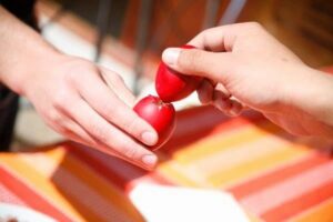 Two hands holding and cracking a red dyed egg each. This is part of Easter celebrations in Greece