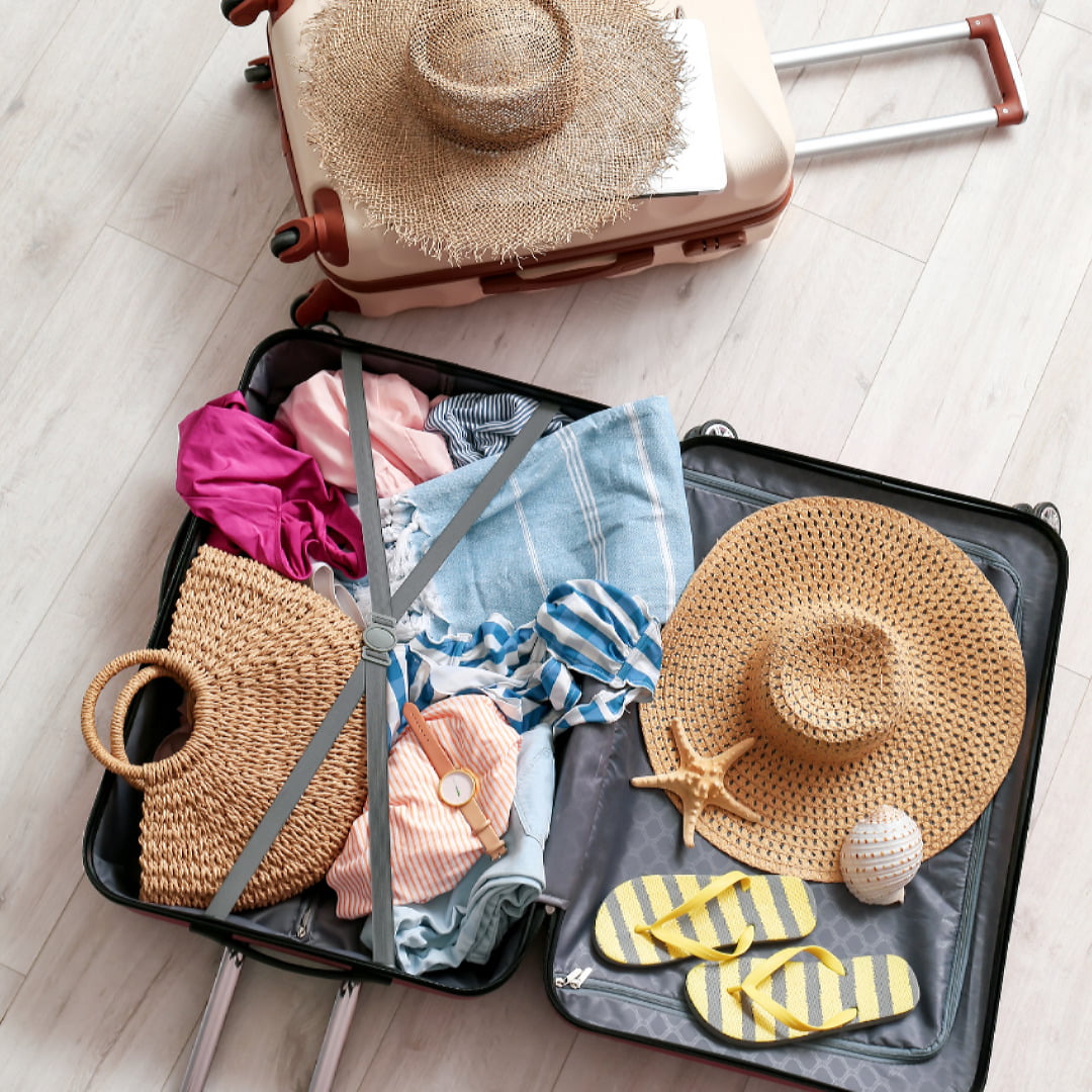 An open suitcase with summer clothes, straw hats and flip flops that are included in stylist Donna Tweedales' suggestions when packing for Greece