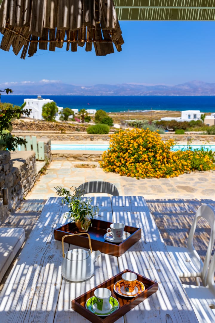 The view of the shared pool and the Aegean Sea as seen from the small private gate of Villa Bunnie, a holiday rental in Paros by Rent A Greek Villa